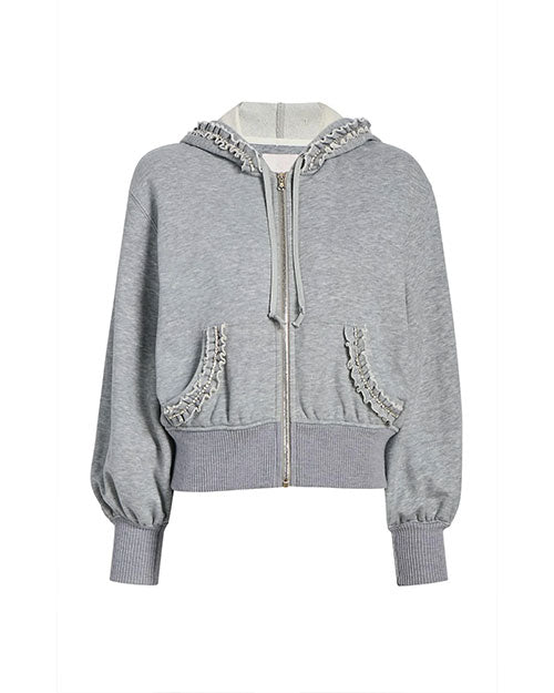  A gray zip-up hoodie with a drawstring hood and long sleeves. The hoodie features ruffled trim detailing along the edge of the hood and around the pocket openings. It has a ribbed waistband and cuffs, creating a slightly cropped and fitted silhouette.