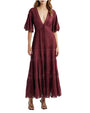 Person wearing a long burgundy dress with a deep V-neckline, elbow-length sleeves, lace accents, and a flowing tiered ankle-length skirt, paired with black sandals.