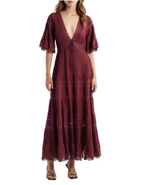 Person wearing a long burgundy dress with a deep V-neckline, elbow-length sleeves, lace accents, and a flowing tiered ankle-length skirt, paired with black sandals.