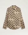 Product image of a cream-colored long-sleeve blouse featuring an allover black floral-inspired print. The blouse has a pointed collar, button-front closure, buttoned cuffs, and a relaxed fit with a gently curved hem. Shown laid flat against a light gray background.