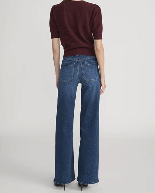 Back view of high-waisted blue wide-leg jeans paired with a short-sleeve textured knit top in deep burgundy and black pointed shoes.
