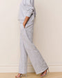 Side view of a light gray loungewear set featuring a relaxed-fit sweatshirt and wide-leg pants with a subtle tonal floral pattern. The outfit is paired with metallic strappy high-heeled sandals.