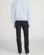 Back view of a person standing in a studio against a light neutral background, wearing a light blue crewneck sweater with ribbed neckline, cuffs, and hem, paired with dark-wash straight-leg jeans. The image is photographed in a full-length, front-facing pose.