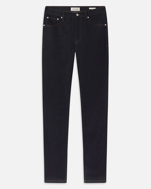 Product image of dark indigo denim jeans displayed flat against a light background, featuring a mid-rise waist, belt loops, a button and zip fly closure, and classic five-pocket styling with metal rivets. The jeans have a slim, straight-leg silhouette with clean lines and minimal visible fading, accented by subtle contrast stitching.