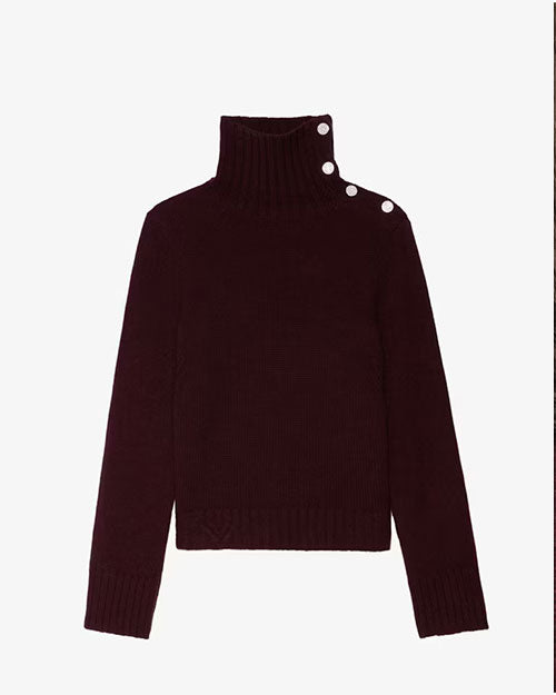 A dark burgundy knit turtleneck sweater with long sleeves and a ribbed texture at the collar, cuffs, and hem. The sweater features three decorative silver buttons along the side of the high neckline, adding a stylish detail to the design.