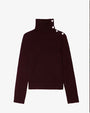 A dark burgundy knit turtleneck sweater with long sleeves and a ribbed texture at the collar, cuffs, and hem. The sweater features three decorative silver buttons along the side of the high neckline, adding a stylish detail to the design.