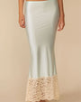 A person shown from the mid‑torso to the ankles is wearing a long, pale mint satin skirt. The skirt has a smooth, slightly glossy finish and a fitted silhouette that flares subtly toward the hem. The bottom portion features a wide band of cream-colored floral lace extending upward from the edge, adding contrast and texture.