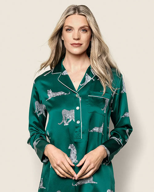Person wearing a green satin pajama top with a white leopard print pattern, featuring a button-down front, long sleeves, a collar, and a left chest pocket.