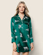 Person wearing a green satin nightshirt with white leopard prints, featuring a collar, long sleeves, button-down front, and white piping along the edges and cuffs.