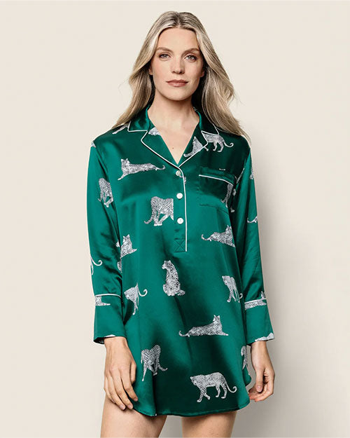 Person wearing a green satin nightshirt with white leopard prints, featuring a collar, long sleeves, button-down front, and white piping along the edges and cuffs.