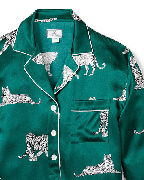 Green satin pajama top with a white leopard print pattern, featuring a collar, white piping along the edges and cuffs, a button-down front, and a left chest pocket with piping detail. The label inside reads "Petite Plume."
