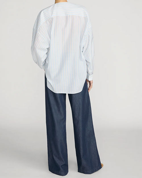 Blue and white striped oversized button-front shirt with a split neckline, paired with dark wash wide-leg jeans.