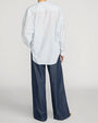 Blue and white striped oversized button-front shirt with a split neckline, paired with dark wash wide-leg jeans.