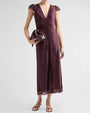 Sleeveless midi-length dress in a deep plum or burgundy shade featuring a V-neckline, lace trim along the neckline and front button placket, and a fitted silhouette. The dress has a front slit and a lace-trimmed hem. The model holds a matching burgundy clutch and wears black thong sandals against a light gray background.