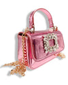 Side view of a small metallic pink handbag with a top handle, a front flap featuring a large rectangular crystal embellishment, and a gold chain strap draped alongside.