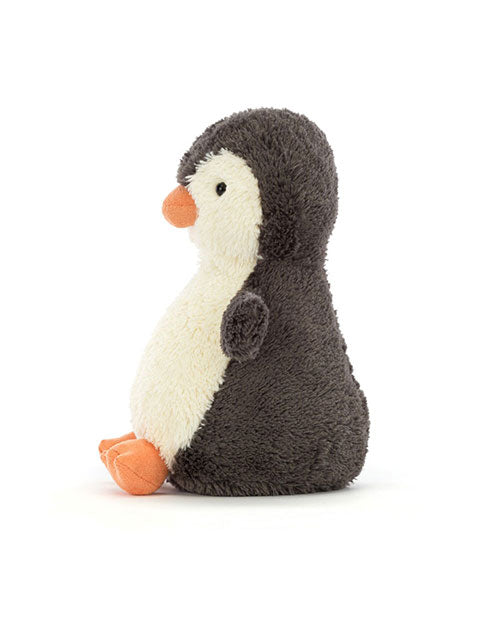 Plush penguin toy sitting upright and facing left, with dark grey fur on its body, a white belly and face, and orange beak and feet.