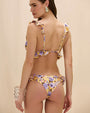 Rear-view of a person wearing a yellow ruffle bikini with a purple floral print. 