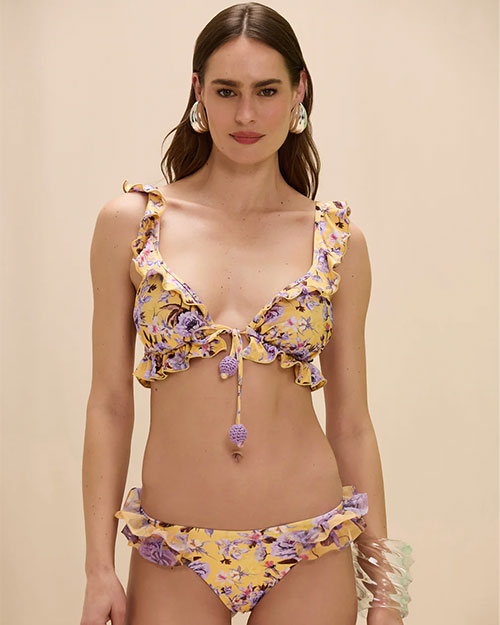 Person wearing a yellow ruffle bikini with purple floral print.