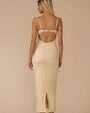 Back view of a person wearing a fitted, cream-colored textured dress with a long, straight silhouette that extends to mid-calf. The dress features structured cups with a small cutout detail beneath them and thin shoulder straps tied in small knots at the top. The fabric has a nubby, boucle-like texture throughout.