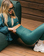 A model wearing a pine green polka dotted sports bra and leggings set