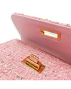 Close-up of the interior of a pink tweed handbag with sequins, showing a gold-tone twist-lock closure and pink lining.