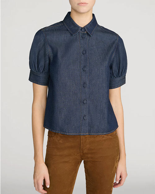 A person wearing a dark denim, button down blouse with short puff sleeves and a collar. 