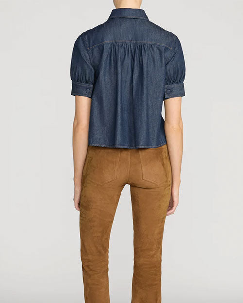 Rear view of a person wearing a dark denim, button down blouse with short puff sleeves and a collar. 