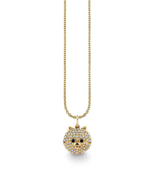 Gold necklace featuring a round pendant shaped like a pomeranian's face, fully encrusted with small white pavé-set gemstones. The pendant includes black gemstone eyes and a tiny nose detail, hanging from a delicate gold chain.