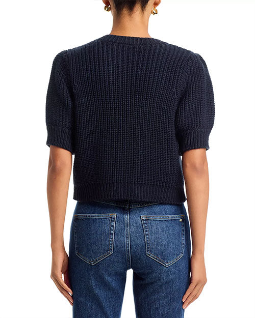Rear view of a navy cropped knit cardigan with short puff sleeves paired with blue jeans.