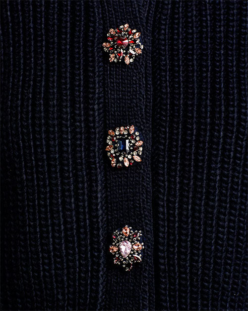 Close-up of decorative jeweled buttons on a navy knit sweater.