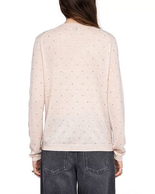 Back view of a person wearing a light pink long-sleeve sweater embellished with small, evenly spaced rhinestones. The sweater has a straight hem and a relaxed fit. It is paired with high-waisted, faded black jeans featuring visible back pockets. The person’s arms are relaxed by the sides, and long straight hair falls down the back.