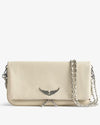 Front view of an ivory leather clutch bag featuring a silver wing emblem on the flap, a silver chain strap, and zipper detail, displayed against a light background.