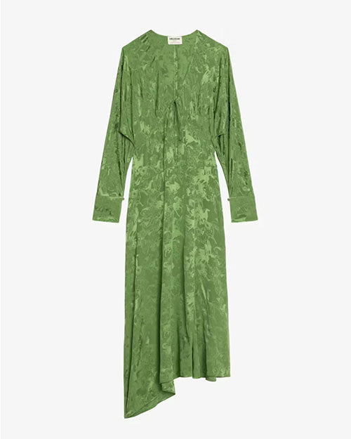  A long-sleeve green dress displayed against a plain background. The dress features a subtle textured pattern, a V-neckline with a small tie detail at the center, and an asymmetrical hemline with one side longer than the other. The fabric appears soft and flowy, with a slightly shiny finish.