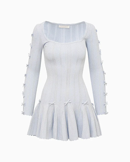 Light blue long-sleeve knit mini dress with a scoop neckline, fitted bodice, and flared hem. The sleeves feature multiple oval cutouts tied with small bows along the arms, and small bow accents are placed at the waistline above the skirt.