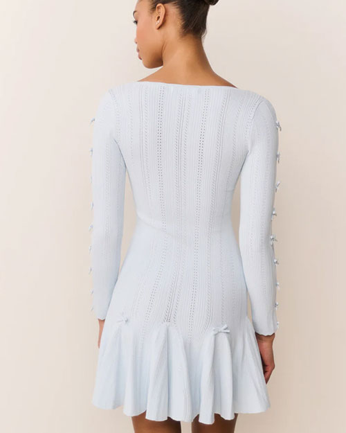 Back view of a light blue long-sleeve knit mini dress with a fitted silhouette and flared hem. The sleeves feature multiple oval cutouts tied with small bows along the arms.