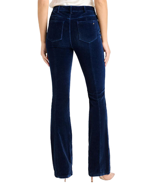 Back view of dark blue velvet pants with a high waist, two back patch pockets, and a slight flare at the hem, paired with nude heels.