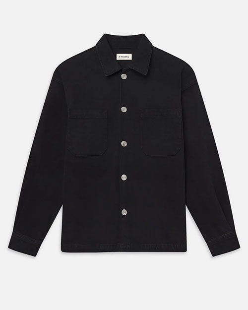 A black button-front overshirt jacket with a pointed collar, white contrast buttons, and two large chest patch pockets.