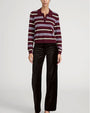 Model wearing a burgundy and white striped collared knit sweater paired with brown wide-leg pants.