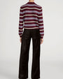 Model wearing a burgundy and white striped collared knit sweater paired with black wide-leg pants.