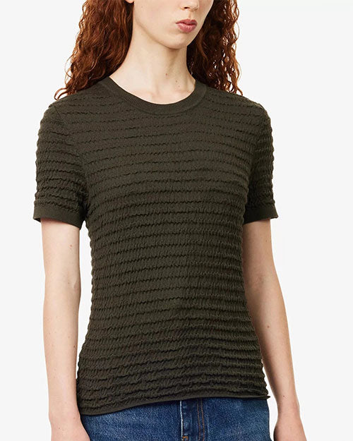 Close-up front view of a textured knit short-sleeve sweater in a dark olive-brown color. The sweater features a crew neckline, ribbed trim at the neck and sleeves, and an allover wavy horizontal textured pattern. The fitted silhouette falls to the hips and is paired with blue denim jeans. The image is shown against a light gray background.