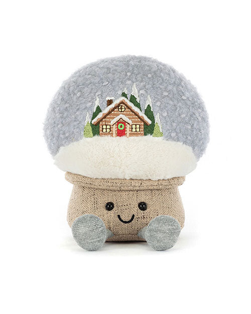 Plush toy shaped like a mushroom with a fluffy light gray cap featuring an embroidered snowy cabin scene, a burlap-textured stem, two light blue feet, and a smiling face with black eyes.