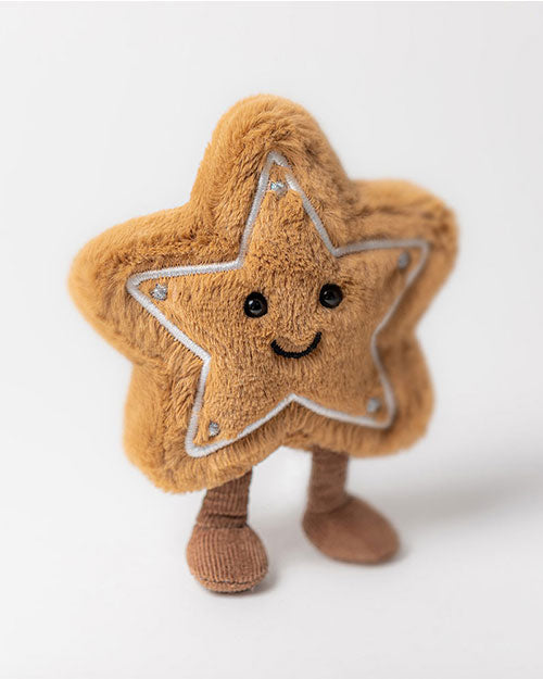 Plush toy shaped like a light brown star with five points outlined in white stitching and silver dots at the tips, featuring black button eyes, a smiling mouth, and two short brown legs resembling socks or boots.