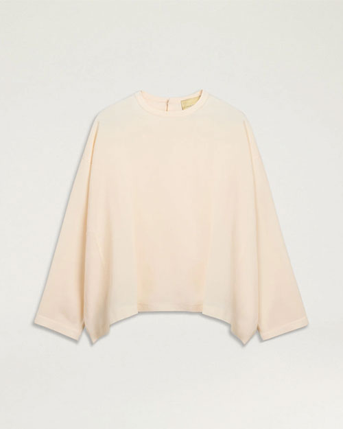 Cream long-sleeve blouse with a relaxed fit, crew neckline, and subtle high-low hem.