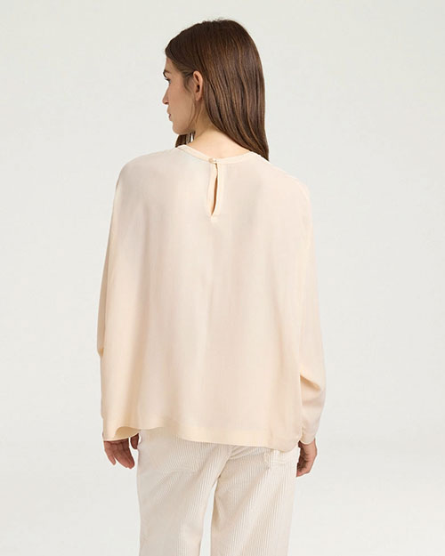 Back view of a cream long-sleeve blouse with a relaxed fit and keyhole button closure at the neckline.