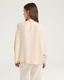 Back view of a cream long-sleeve blouse with a relaxed fit and keyhole button closure at the neckline.