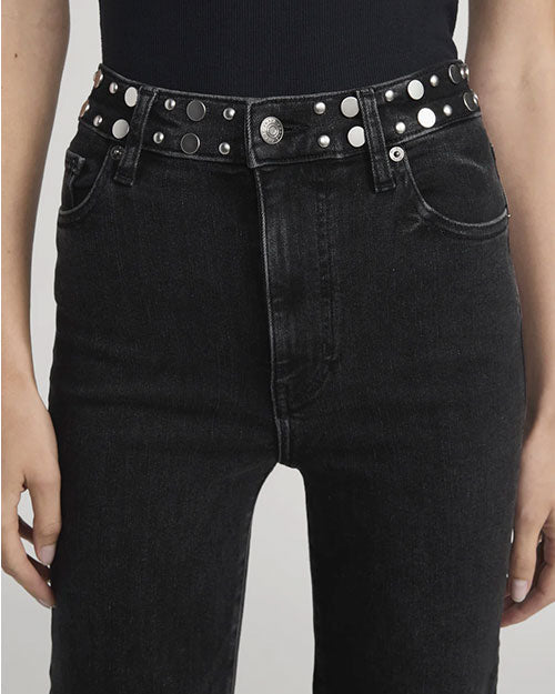 Close-up of high-waisted black jeans paired with a black belt featuring silver studs and a round metal buckle.