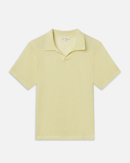 Product image of a pale yellow short-sleeve polo shirt displayed flat against a light background, featuring a soft collar, an open neckline without visible buttons, and a clean, minimal silhouette with a relaxed fit.