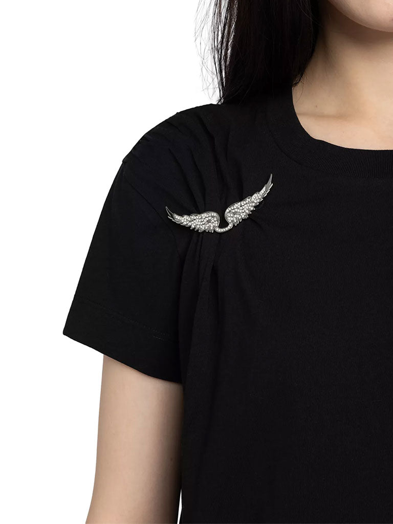 Close up of a black short‑sleeve t‑shirt featuring a small white winged emblem near the left shoulder.