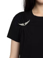 Close up of a black short‑sleeve t‑shirt featuring a small white winged emblem near the left shoulder.