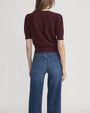 Back view of a short-sleeve textured knit top in deep burgundy paired with high-waisted blue jeans featuring back patch pockets.